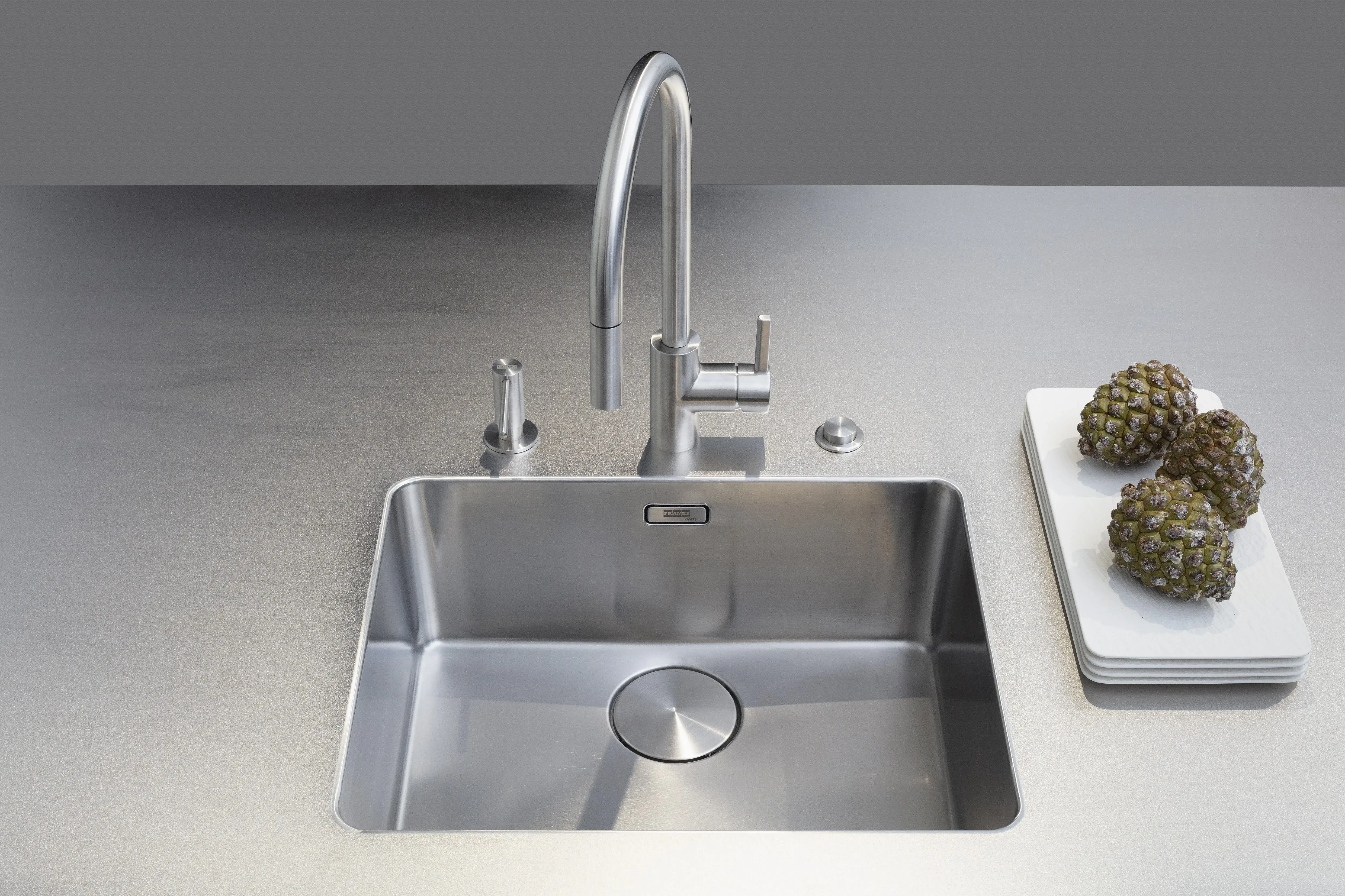 Front: Industriestahl Metalliclack geschliffen AV6000 NCS Mattlack APL: Franke Edelstahl 6 mm Geräte: Bora Spüle Armaturen: Franke  Features: Metallfront, Spülbecken in APL integriert (aus einem Guss), Oberschränke mit Lowboard-Charakter, integrierter Arbeitsplatz, dunkler Korpus mit Aluminium-Abschlussleiste, Wärmeschublade mit Gittereinsatz.