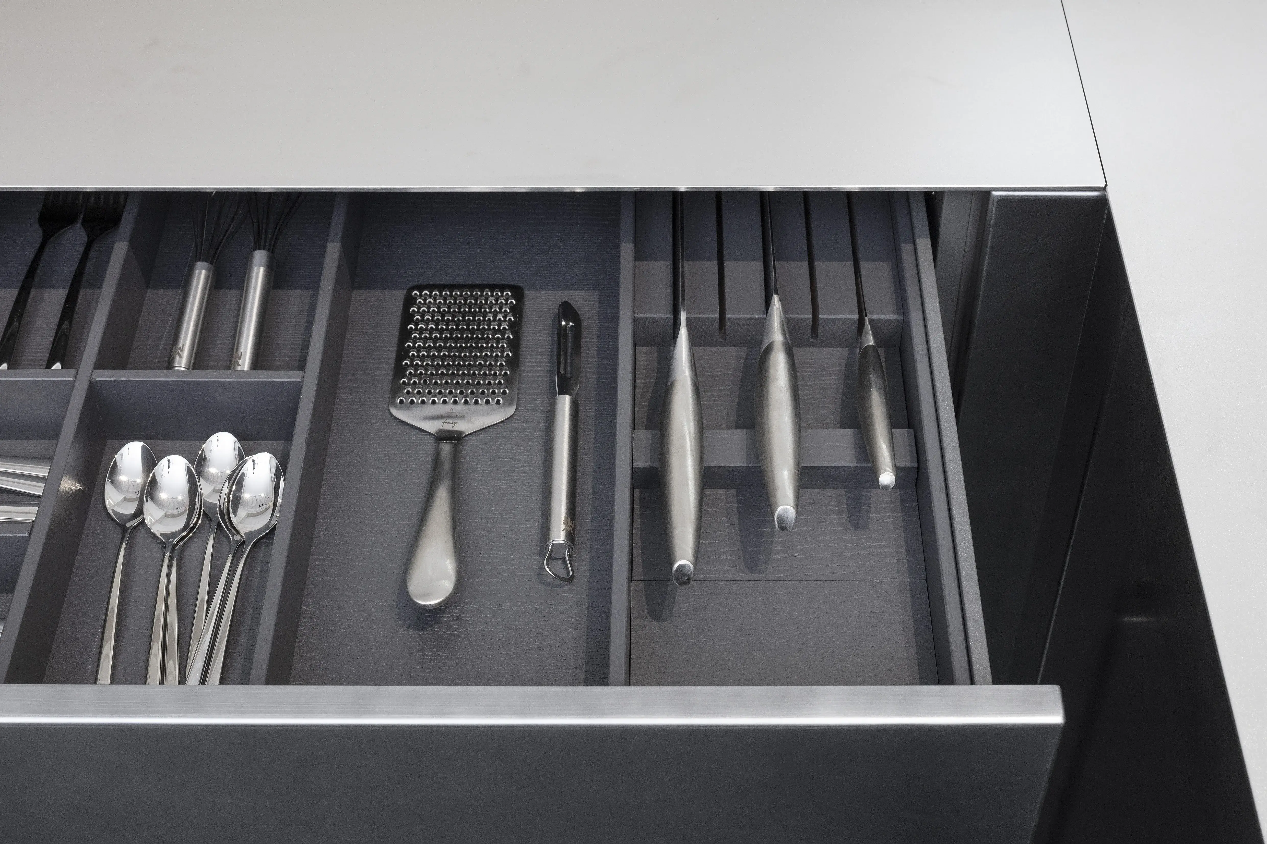 Front: Industriestahl Metalliclack geschliffen AV6000 NCS Mattlack APL: Franke Edelstahl 6 mm Geräte: Bora Spüle Armaturen: Franke  Features: Metallfront, Spülbecken in APL integriert (aus einem Guss), Oberschränke mit Lowboard-Charakter, integrierter Arbeitsplatz, dunkler Korpus mit Aluminium-Abschlussleiste, Wärmeschublade mit Gittereinsatz.